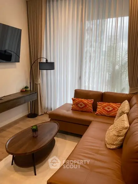 Stylish living room with leather sofa, modern decor, and natural light through large windows.