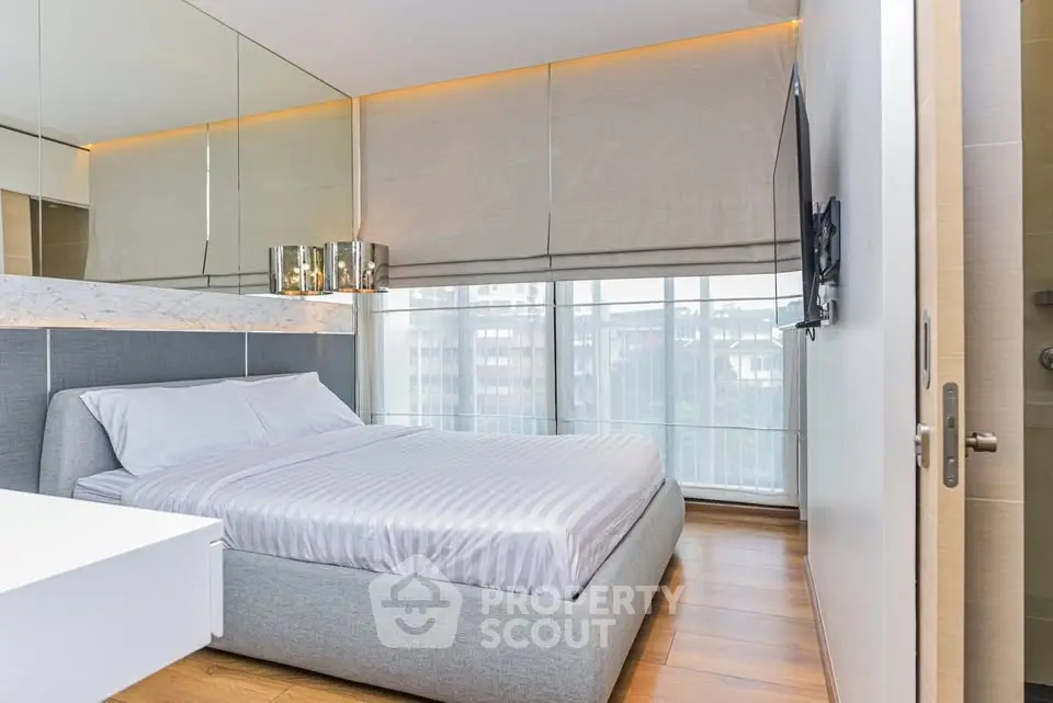 Modern bedroom with large windows and stylish decor in a luxury apartment.