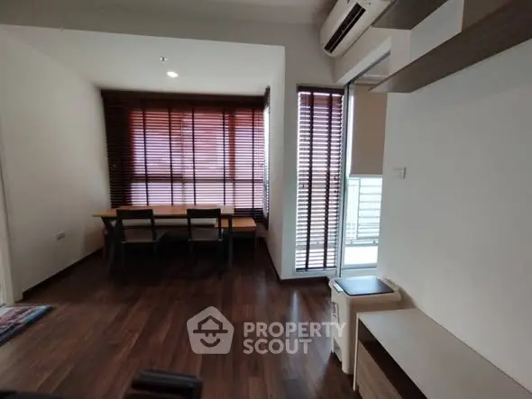 Modern living room with wooden flooring and stylish blinds, featuring a cozy dining area and air conditioning.