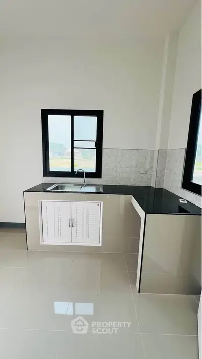 Modern kitchen with sleek countertops and large windows for natural light.