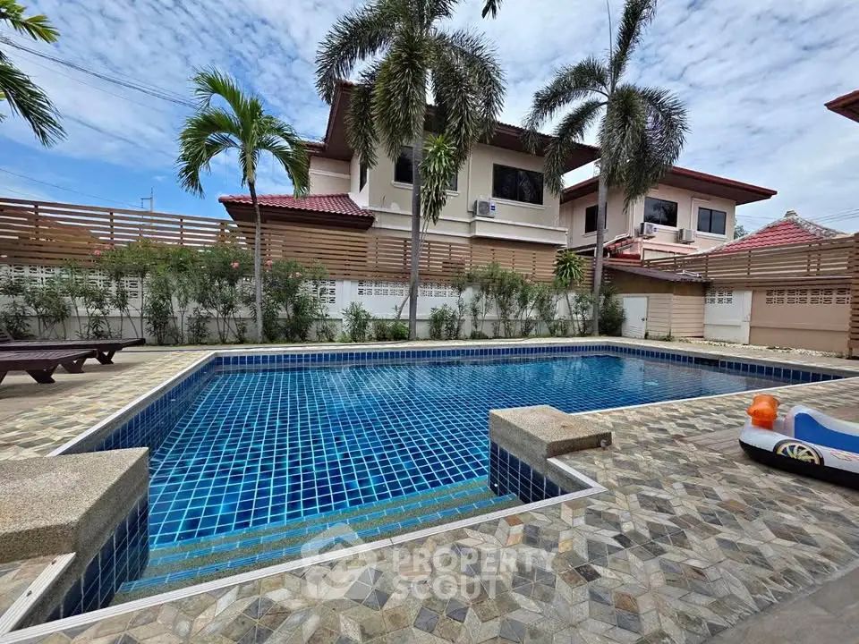 Luxurious residential pool area with palm trees and modern houses, perfect for relaxation and leisure.