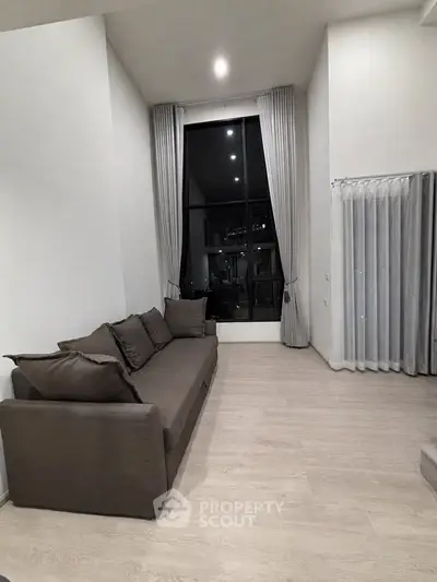 Spacious modern living room with high ceilings and large window view.