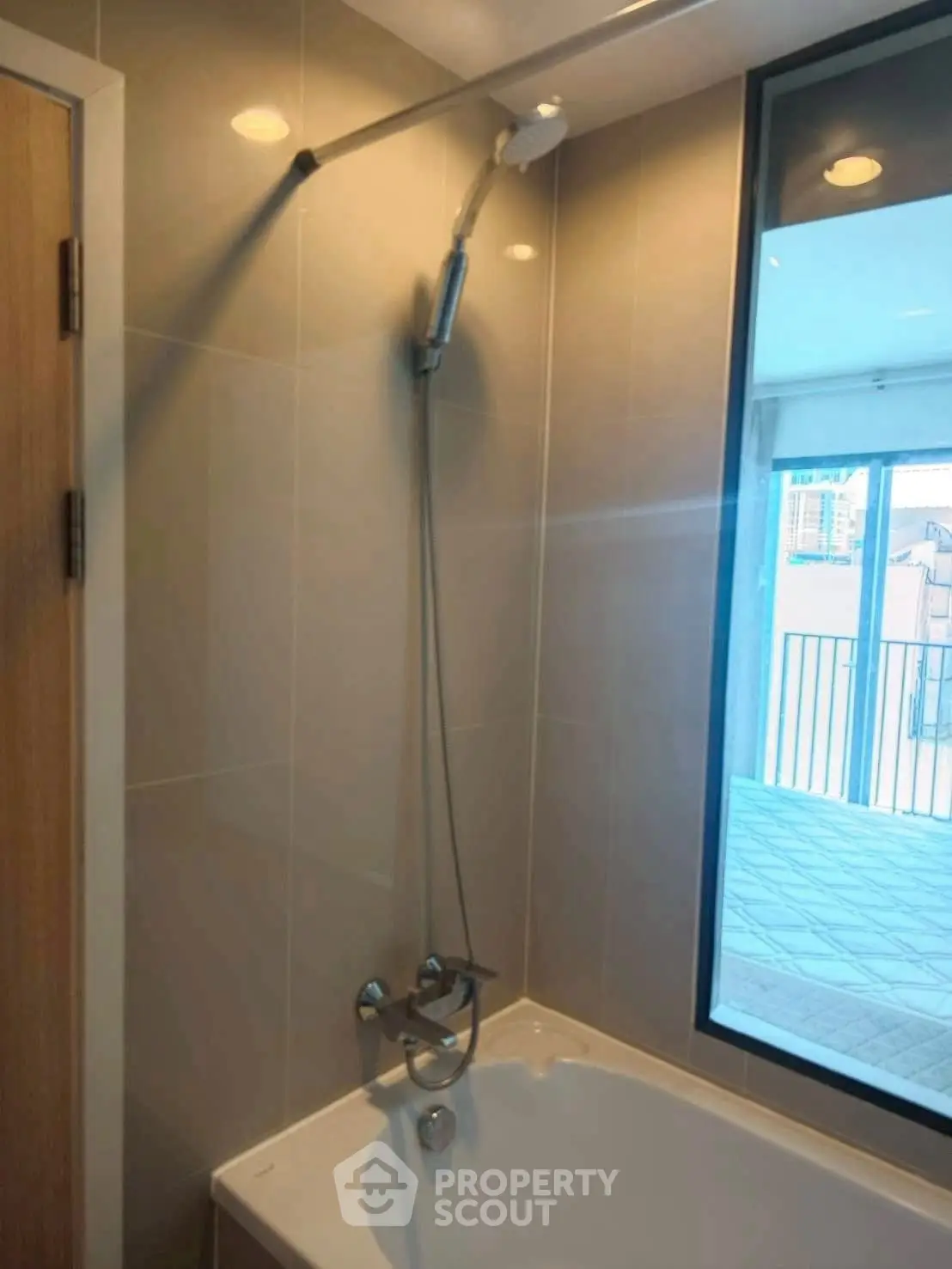 Modern bathroom with bathtub and large window offering city view.