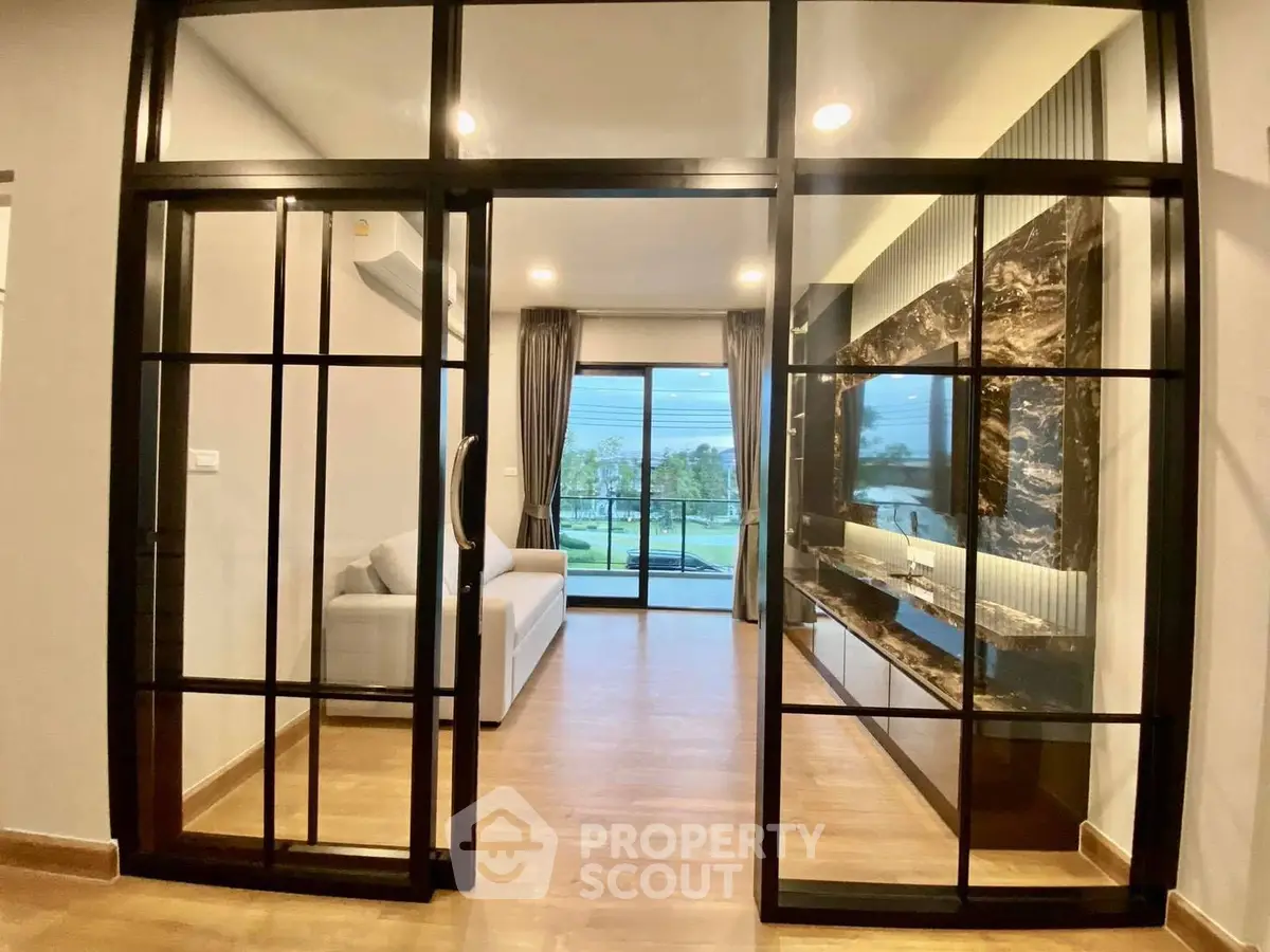 Modern living room with glass doors and scenic view, featuring stylish decor and cozy ambiance.