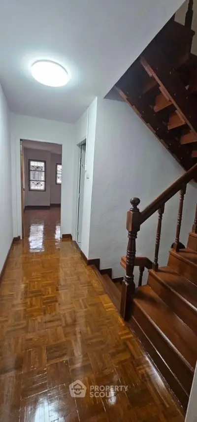 Charming wooden staircase and hallway with polished floors in a cozy home.