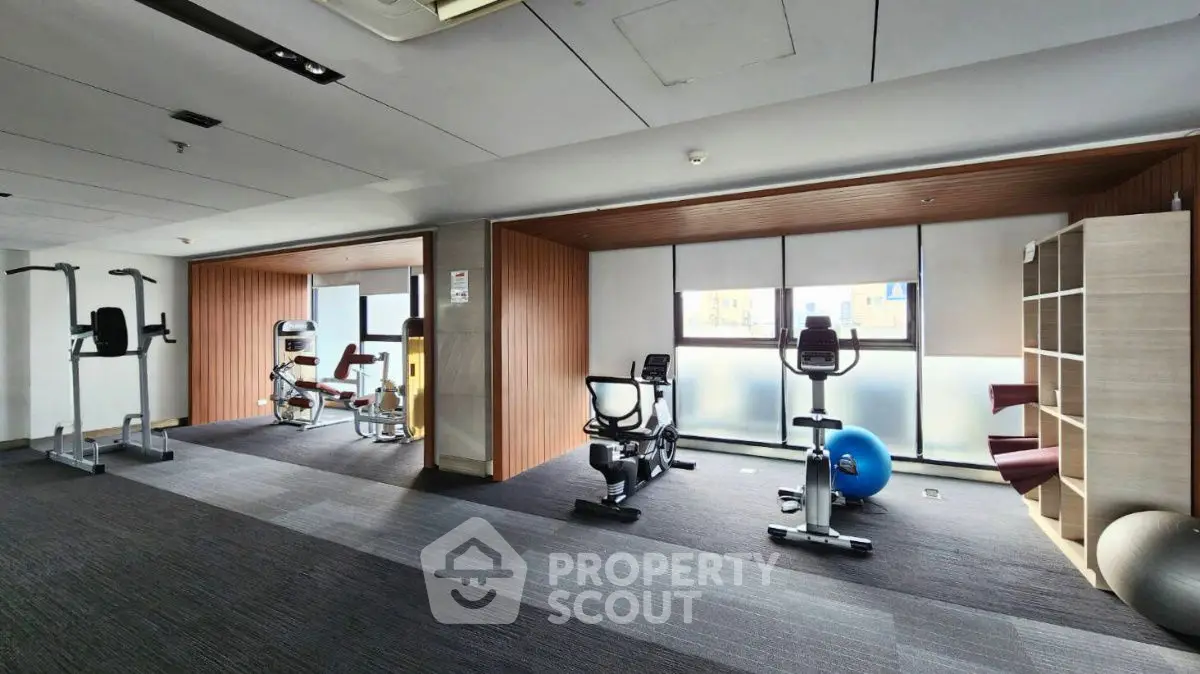 Modern gym with exercise equipment and natural light in upscale residential building.