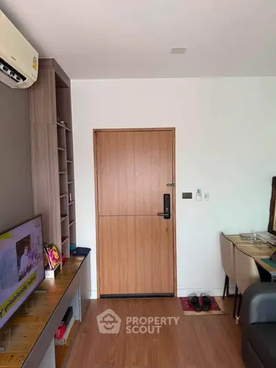 Modern living room with wooden flooring and stylish furniture, featuring a TV and air conditioning.