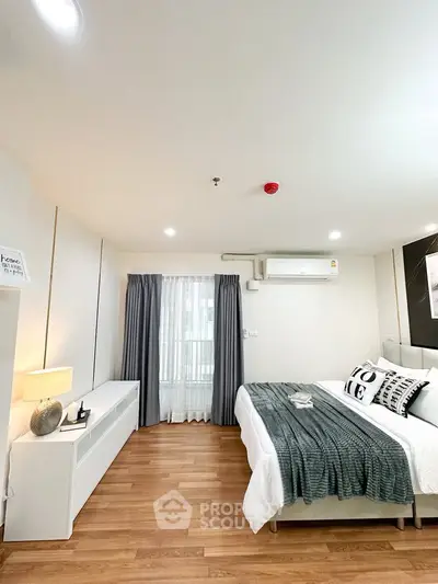 Modern bedroom with stylish decor and natural light, featuring wooden flooring and cozy ambiance.