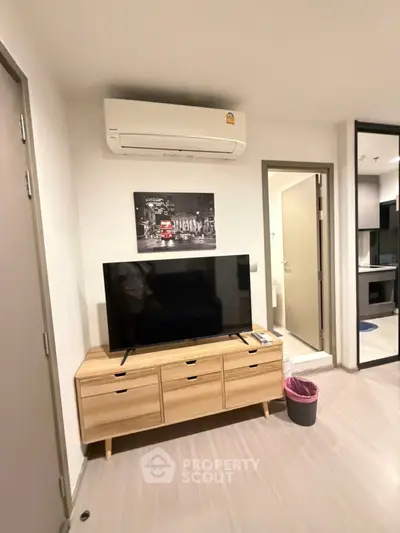 Modern living room with TV, air conditioner, and stylish wooden cabinet.