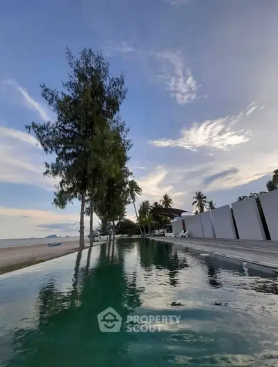 Stunning beachfront pool with palm trees and serene ocean view at luxury property.