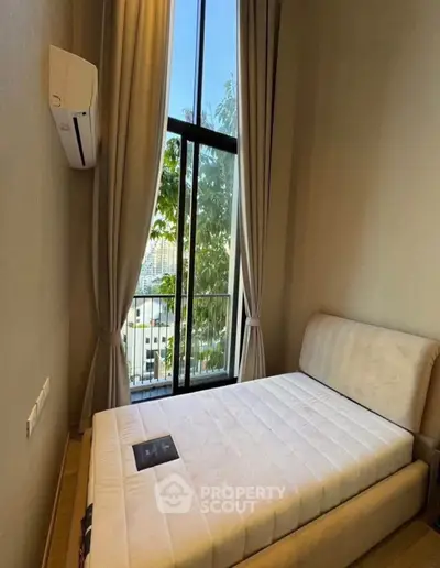 Modern bedroom with large window and city view, featuring a comfortable bed and air conditioning.