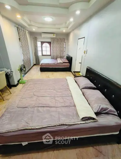 Spacious bedroom with two beds, elegant ceiling design, and ample natural light.