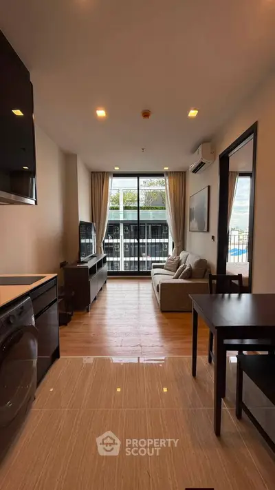 Modern living room with balcony view, stylish furniture, and natural light in a contemporary apartment.