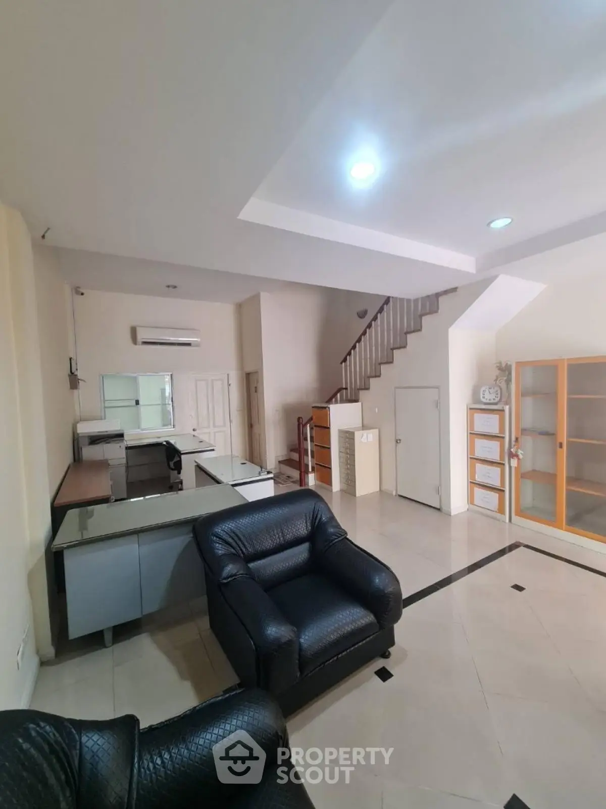 Spacious living room with modern furniture and open layout, featuring a staircase and ample natural light.