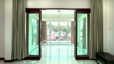 Spacious living room with large windows and elegant curtains, offering abundant natural light and a serene view.