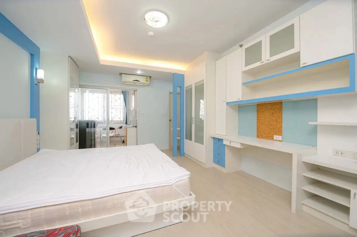 Spacious modern bedroom with built-in desk and ample storage in a bright apartment.