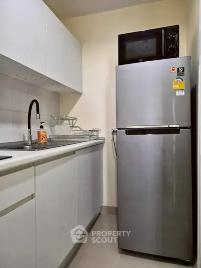Modern kitchen with sleek fridge and white cabinetry, perfect for urban living.