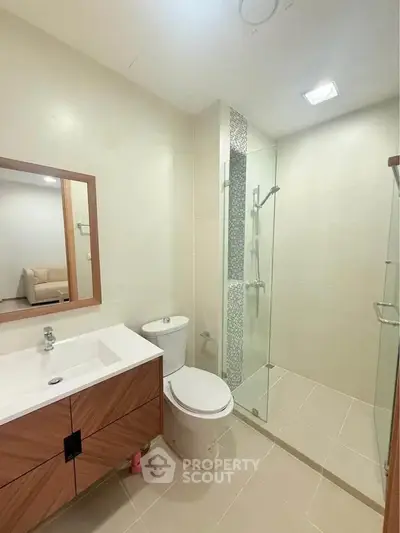 Modern bathroom with glass shower and stylish wooden vanity in a contemporary apartment.