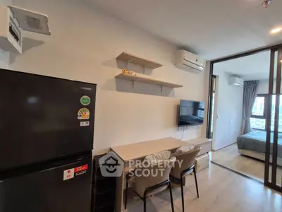 Modern apartment interior with open living and dining area, featuring sleek furniture and a view into the bedroom.