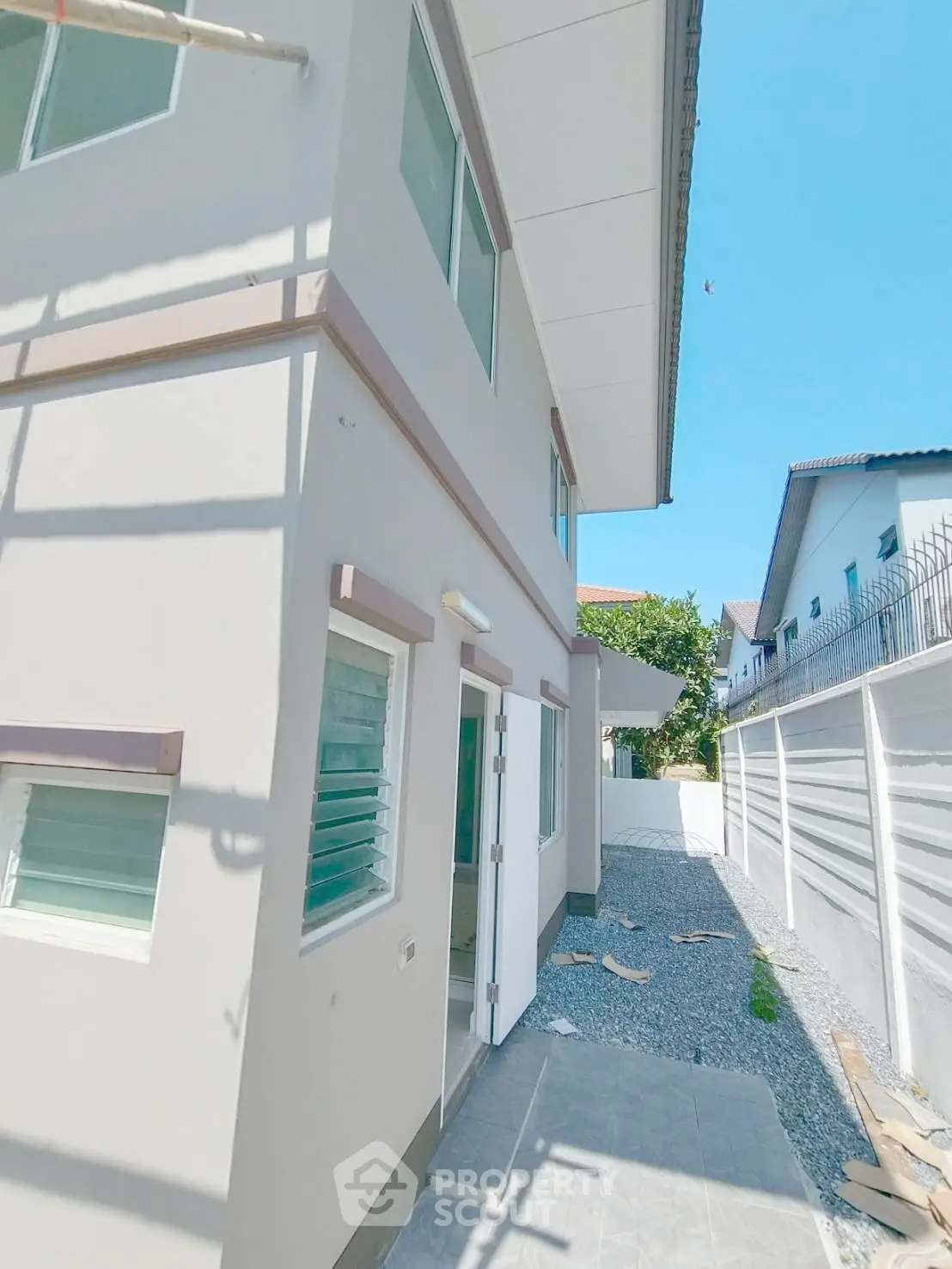 Modern two-story house exterior with clean lines and large windows in a sunny neighborhood.