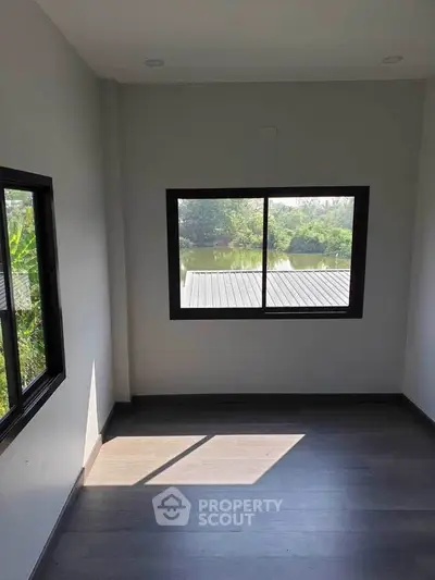 Bright room with large windows offering serene water and greenery view.