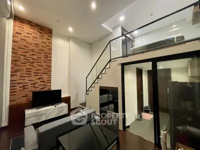 Modern loft-style living room with mezzanine and stylish brick accent wall.