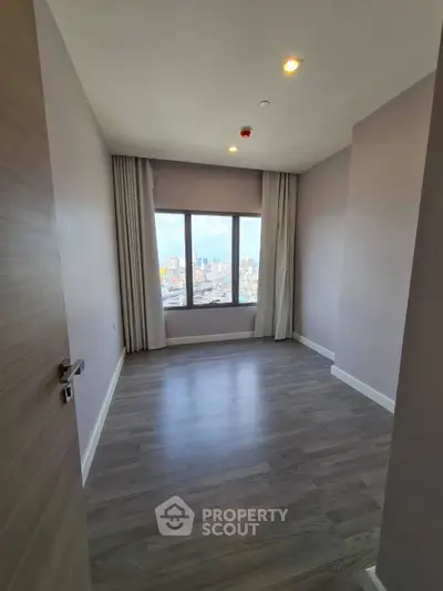 Spacious empty room with large window offering stunning city view, perfect for customization.