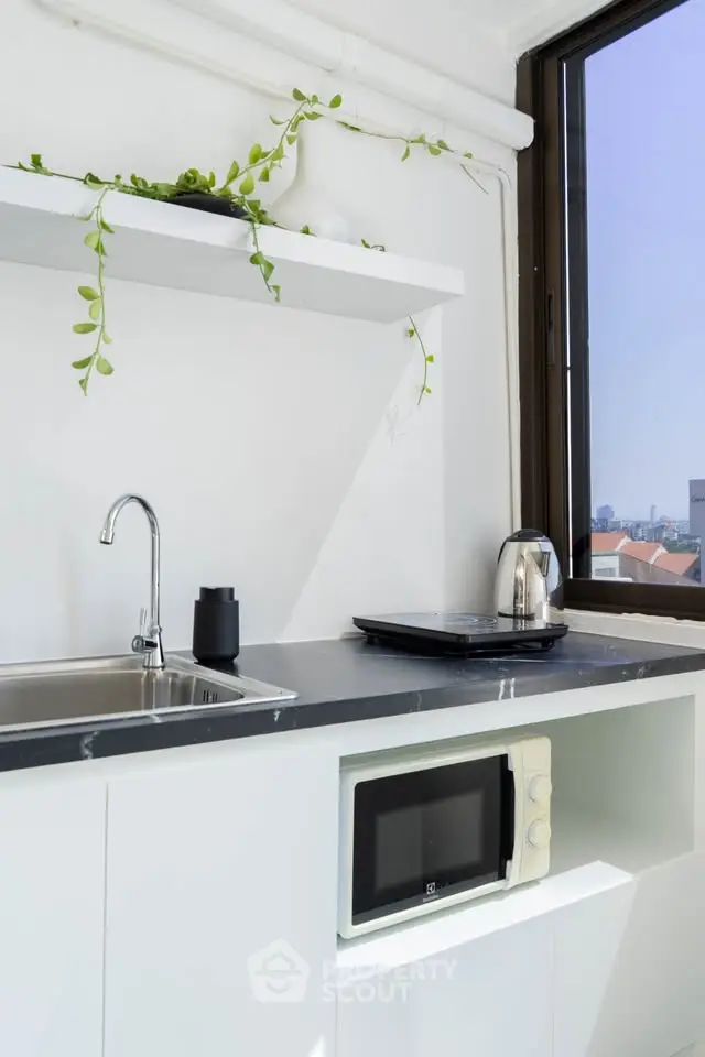 Modern kitchen with sleek design, featuring a microwave, sink, and city view window.