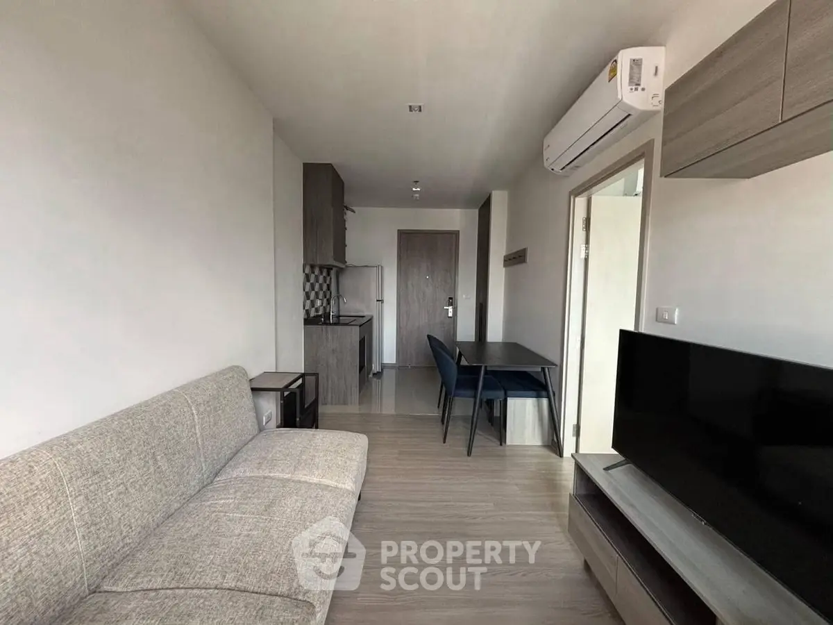 Modern living room with sleek furniture and compact kitchen area.