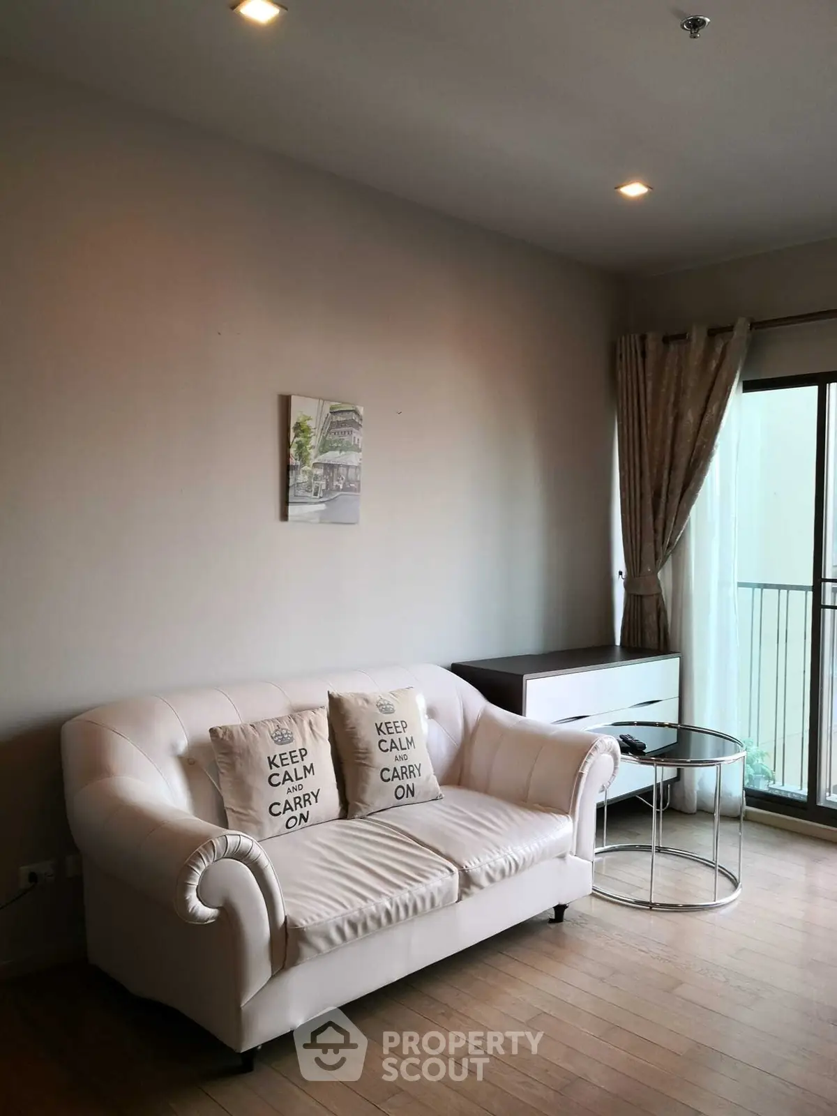 Chic living room with elegant white sofa and balcony access, perfect for modern urban living.