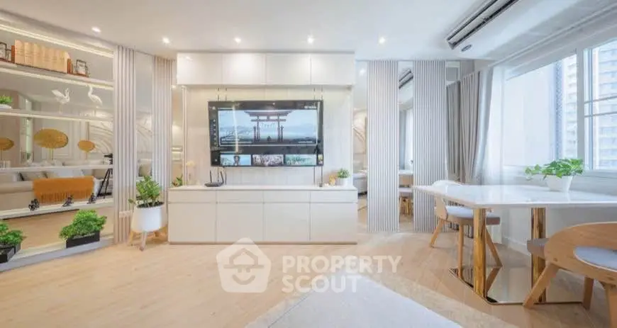 Modern living room with sleek design, large TV, and natural light from big windows, perfect for urban living.