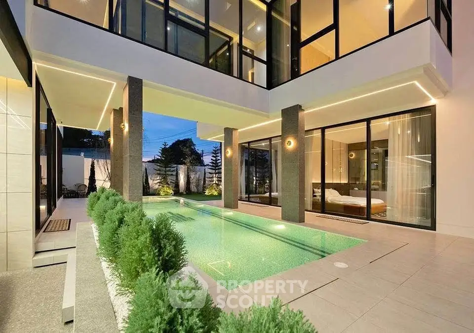 Luxurious modern home with stunning pool and elegant lighting, perfect for relaxation and entertainment.