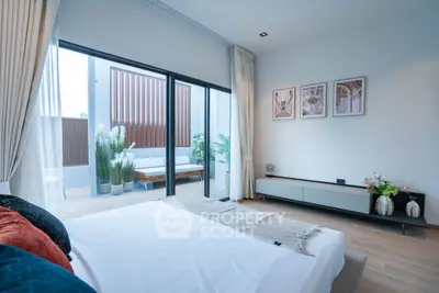 Modern bedroom with large windows opening to a stylish balcony, featuring elegant decor and natural light.