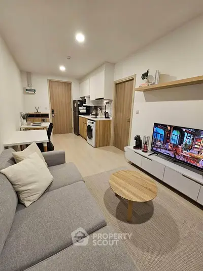 Modern living room with stylish furniture and integrated kitchen appliances in a cozy apartment.