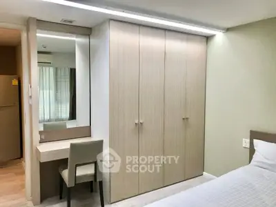 Modern bedroom with built-in wardrobe and vanity desk, featuring sleek design and ample storage space.