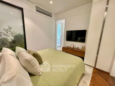 Modern bedroom with green bedding, wall-mounted TV, and sleek decor in a stylish apartment.