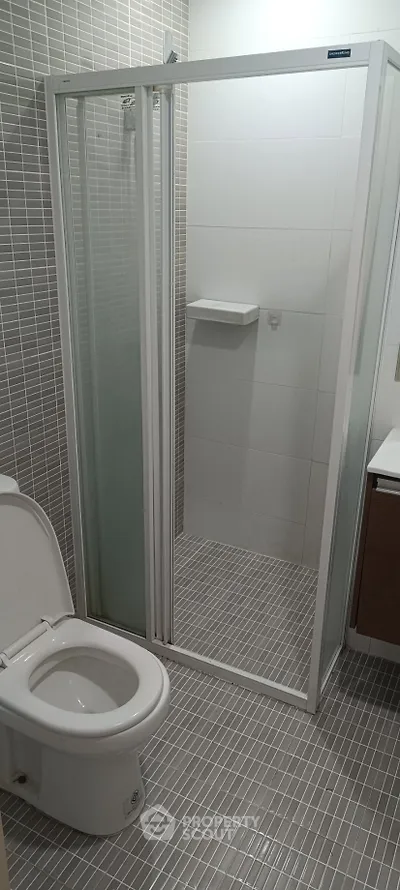 Modern bathroom with sleek shower enclosure and tiled flooring, perfect for contemporary living.