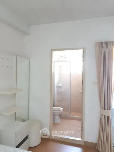 Bright bedroom with ensuite bathroom featuring glass shower door and modern decor.