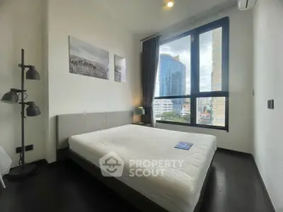 Modern bedroom with large window offering city view, featuring minimalist decor and natural light.