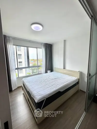 Bright and cozy bedroom with large window and modern furnishings in a high-rise apartment.