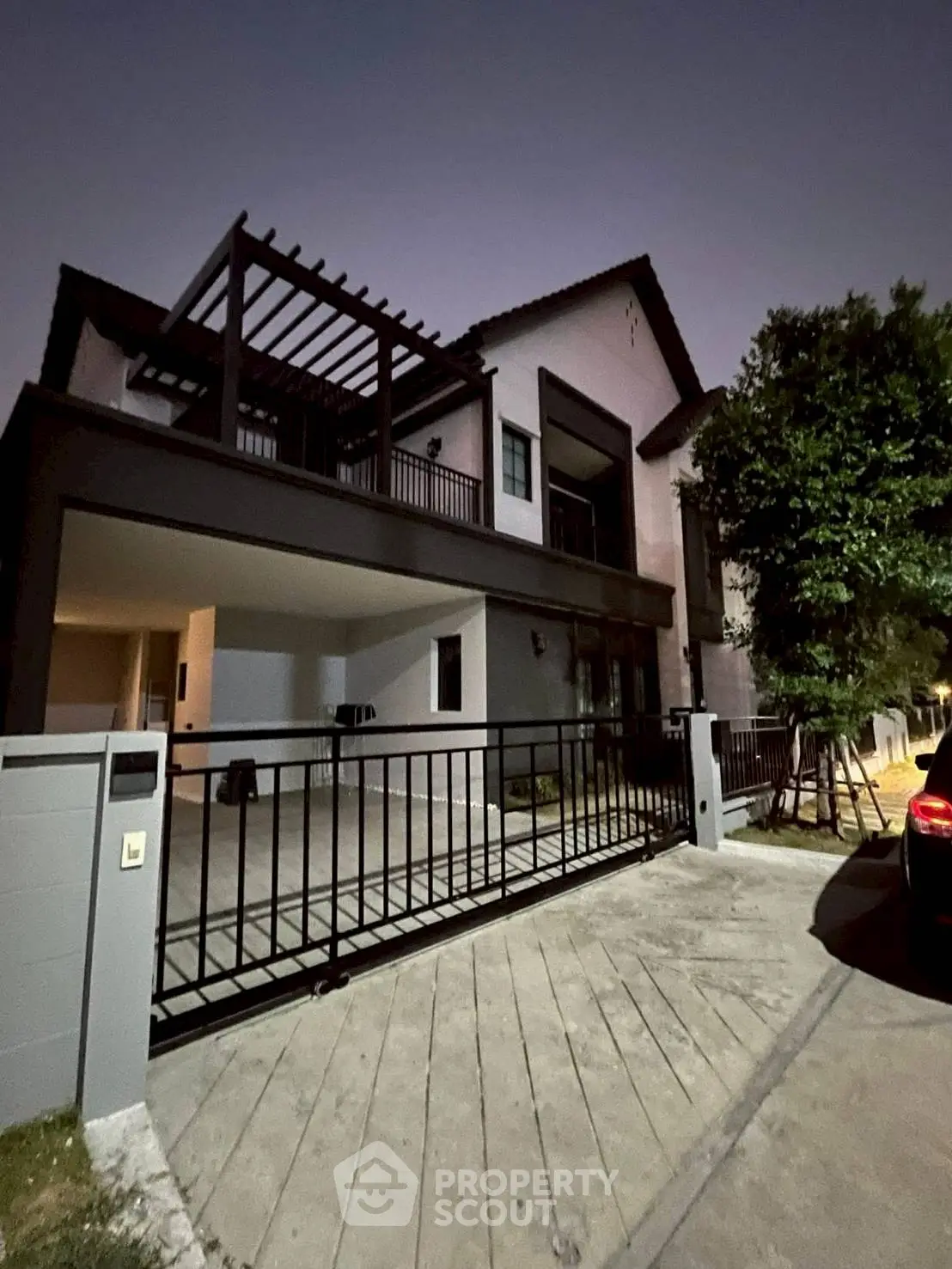 Modern two-story house with spacious driveway and gated entrance at dusk.
