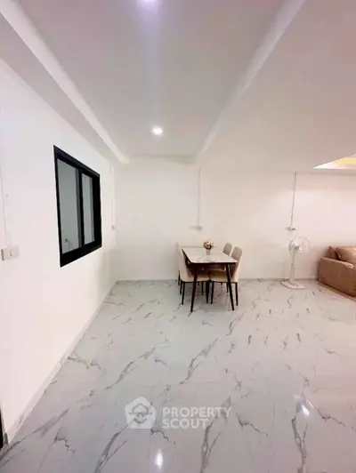 Modern dining area with marble flooring and sleek furniture in a spacious living space.