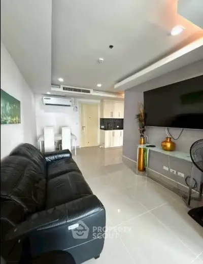Modern living room with sleek black leather sofa and large wall-mounted TV