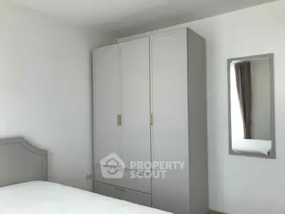 Minimalist bedroom with white wardrobe and mirror, perfect for modern living.