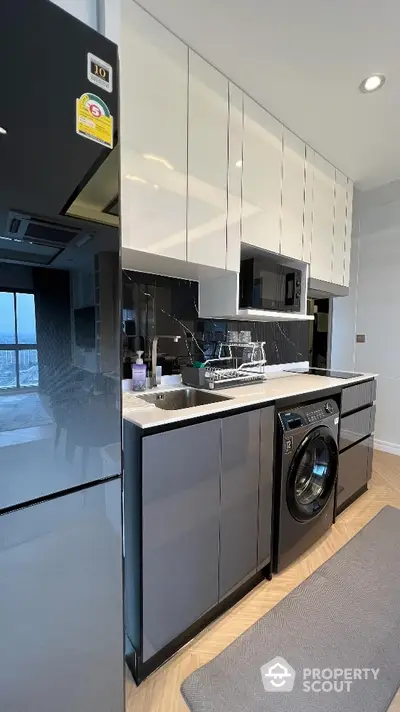 Modern kitchen with sleek cabinetry and built-in washing machine in stylish apartment