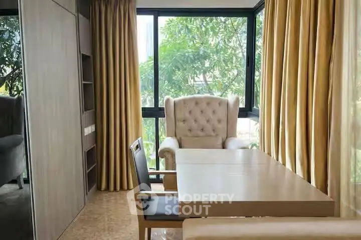 Elegant study room with large windows and plush armchair, perfect for work or relaxation.