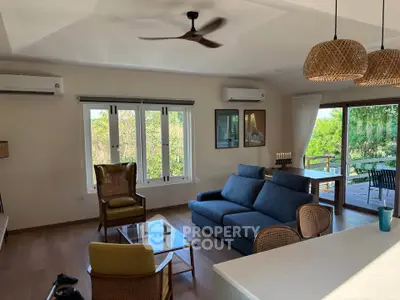 Spacious living room with modern decor and large windows overlooking greenery.