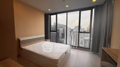 Spacious bedroom with stunning city view and large windows in modern apartment.