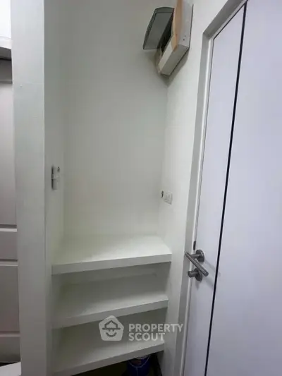 Compact storage space with white shelves and door, ideal for organizing essentials.