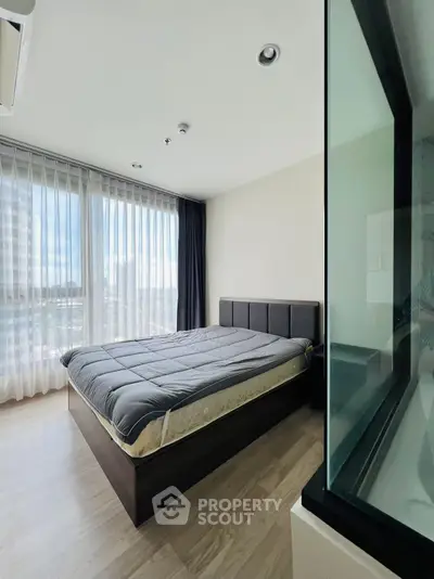 Modern bedroom with large windows and stylish bed in a bright apartment.